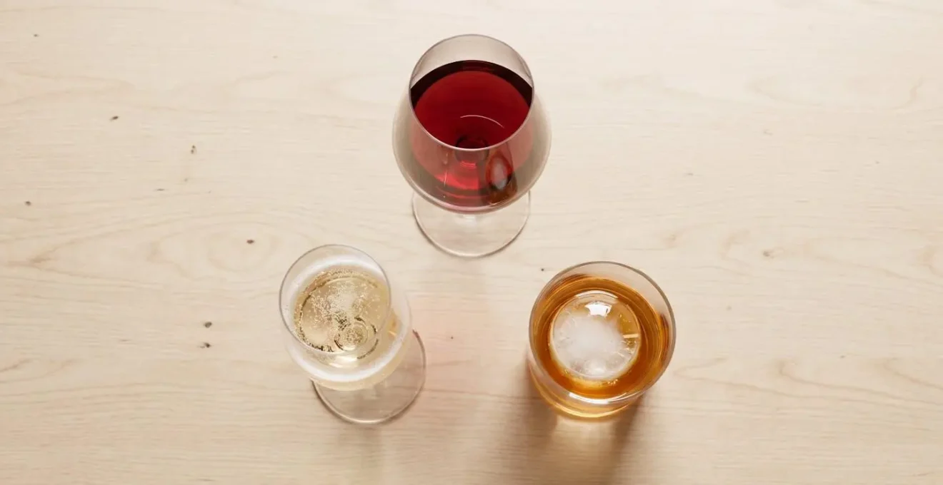 Trois verres Lehmann (vin rouge, champagne, cocktail) disposés sur une table en bois.